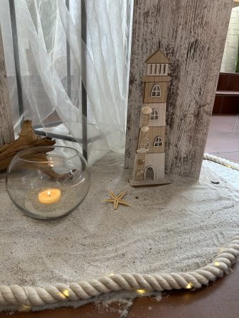 Leuchtturm, Kerze, Seestern und Sand